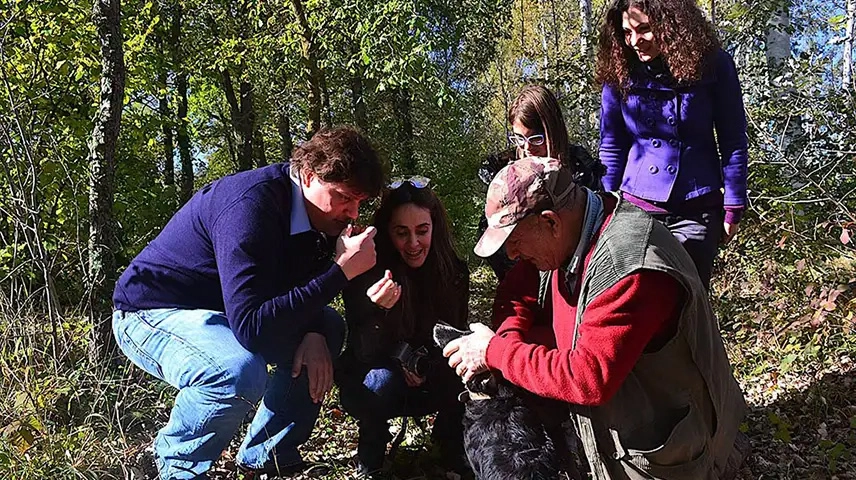 Group of people smelling the just found truffle during a truffle hunt with expert hunter and trained dog